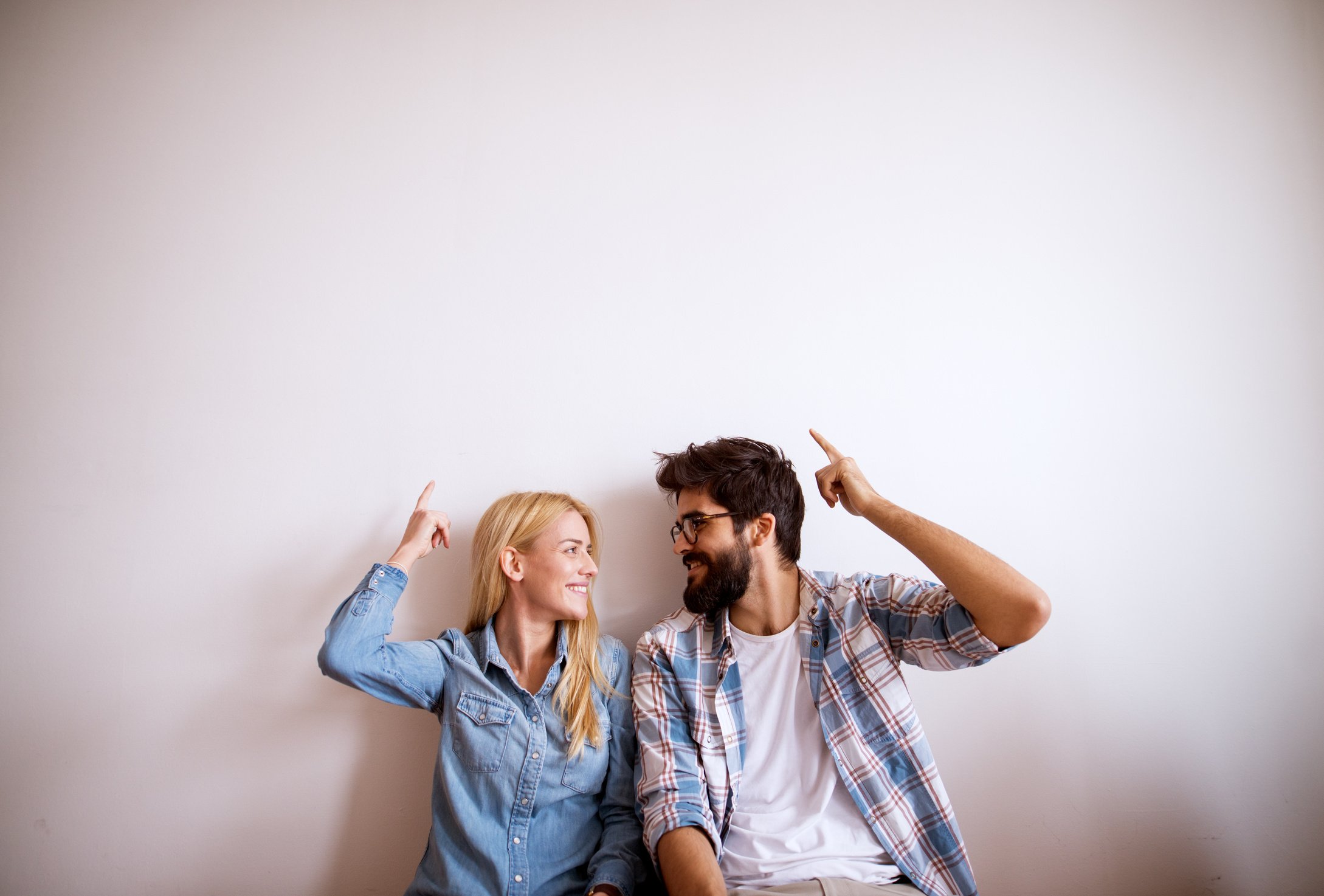 Happy young modern couple standing against the wall.