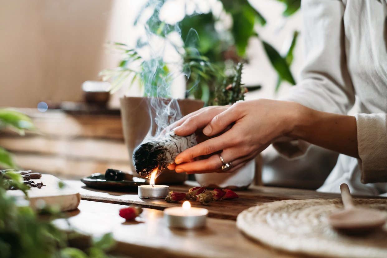 a person is lighting a candle on a wooden table, Spiritual Cleansing Ceremonies